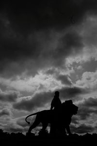 Silhouette people riding horse against sky