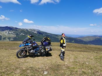 People riding motorcycle on mountain against sky