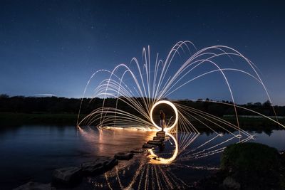 Man standing by wire wool at lakeshore against sky