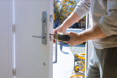 Midsection of carpenter repairing door