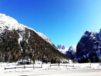 Scenic view of snow covered mountains against clear blue sky