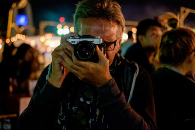 Close-up of man photographing through camera at night
