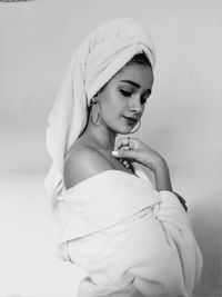 Young woman with wrapped in towel standing against white background