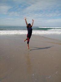 Full length of woman standing on beach against sky