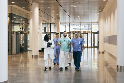 Multiracial group of male and female hospital staff discussing while walking in lobby