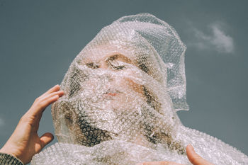 Low angle view of woman with plastic on face against sky