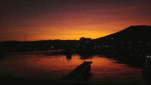 Silhouette of boats in lake during sunset