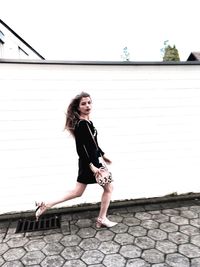 Full length portrait of young woman against clear sky