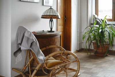 Old fashion wicker rocking chair with blanket in cozy house, lamp on wooden cabinet. place for