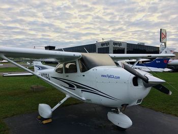 Airplane flying over town against cloudy sky