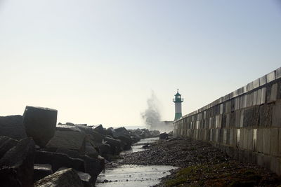 Lighthouse amidst buildings against clear sky