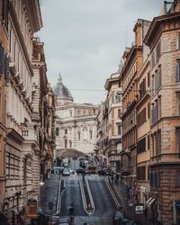 Vehicles on road amidst buildings in city against sky