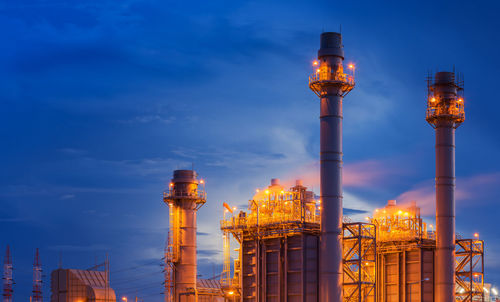 Low angle view of illuminated factory against sky at dusk