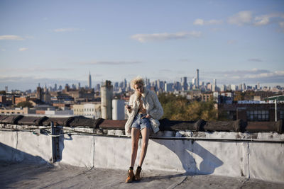 Full length of woman with cityscape against sky