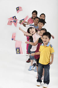 Cute friends waving malaysia flags while standing against white background