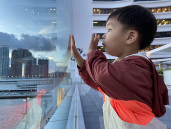 Side view of boy looking through window