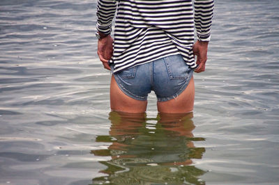 Rear view midsection of woman standing in lake