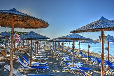 Traditional windmill on beach against clear blue sky