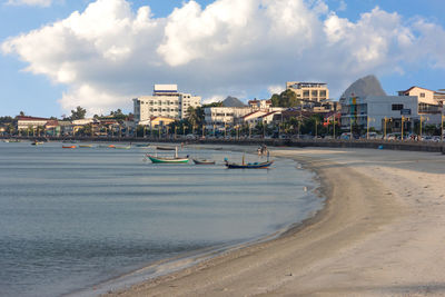 Scenic view of beach by buildings in city against sky