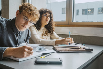 Young multiracial male and female students learning in classroom at community college