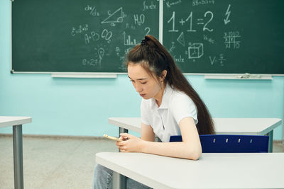 Asian high school girl solves geometry on the blackboard