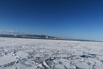 Snow covered landscape against blue sky