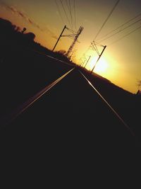 Low angle view of silhouette electricity pylon against sky during sunset