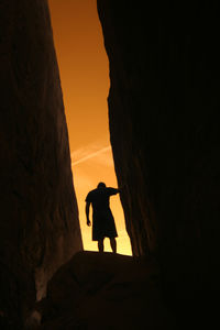 Silhouette man standing on rock formation against sky