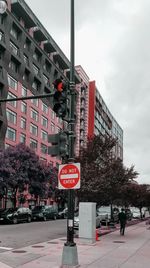 Road sign by building against sky