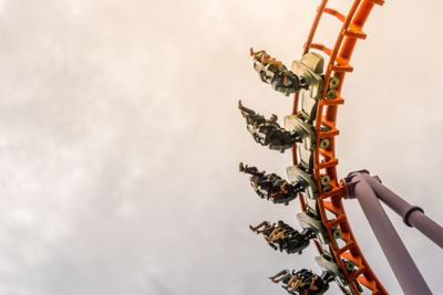 Low angle view of people on rollercoaster against sky