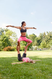 Full length of young woman doing yoga on field against clear sky