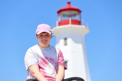 Portrait of smiling teenage girl sitting against lighthouse
