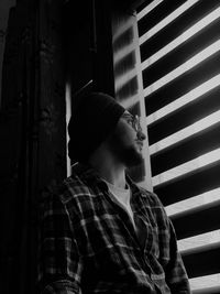 Portrait of young man looking through window