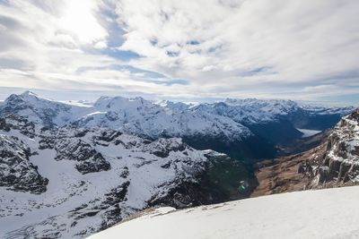 Scenic view of snow covered mountain against cloudy sky