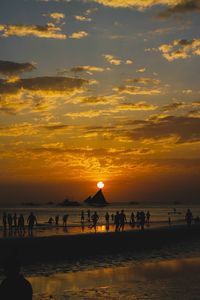 Silhouette people on beach against sky during sunset