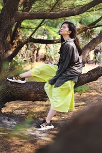 Full length of woman on tree trunk in forest