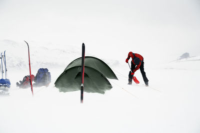 Person digging in snow at camping, sarek national park, lapland, sweden