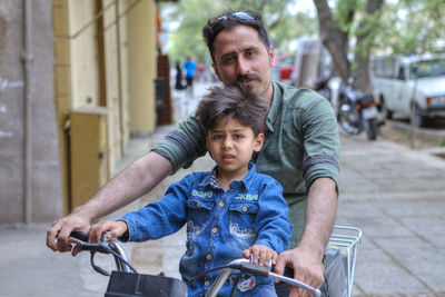 Portrait of father and daughter riding bicycle