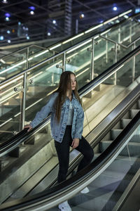 Full length of woman standing on escalator