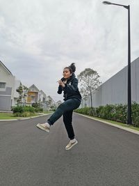 Full length of young woman on road against sky