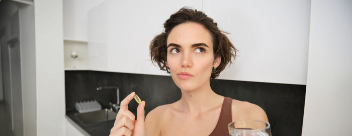 Portrait of young woman drinking water at home