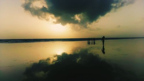 Silhouette man standing on beach against sky during sunset