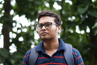 Portrait of young man standing against plants