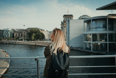 People standing on bridge over river in city against sky