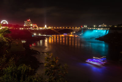 Illuminated bridge over river against sky at night