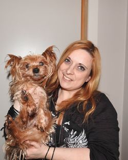 Portrait of smiling woman with dog against wall