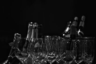Close-up of wineglasses and bottles against black background