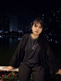 Portrait of young woman standing against sky at night