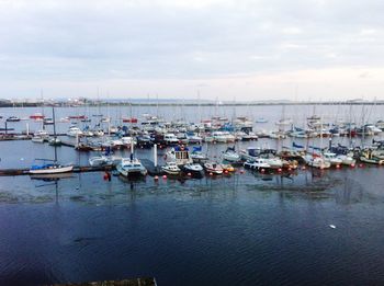 Boats moored at harbor against sky