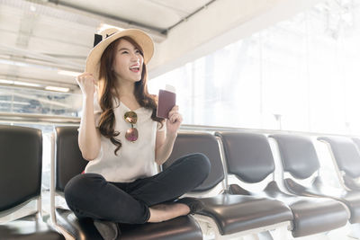 Young woman using phone while sitting on seat